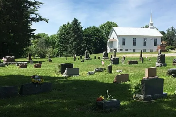 Small white church behind a cemetery.